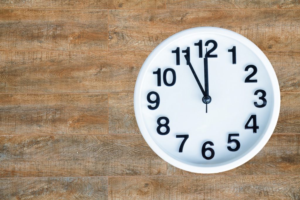 Clock show 5 minute to 12 am or pm on wood background with copy space. clipping path in picture.