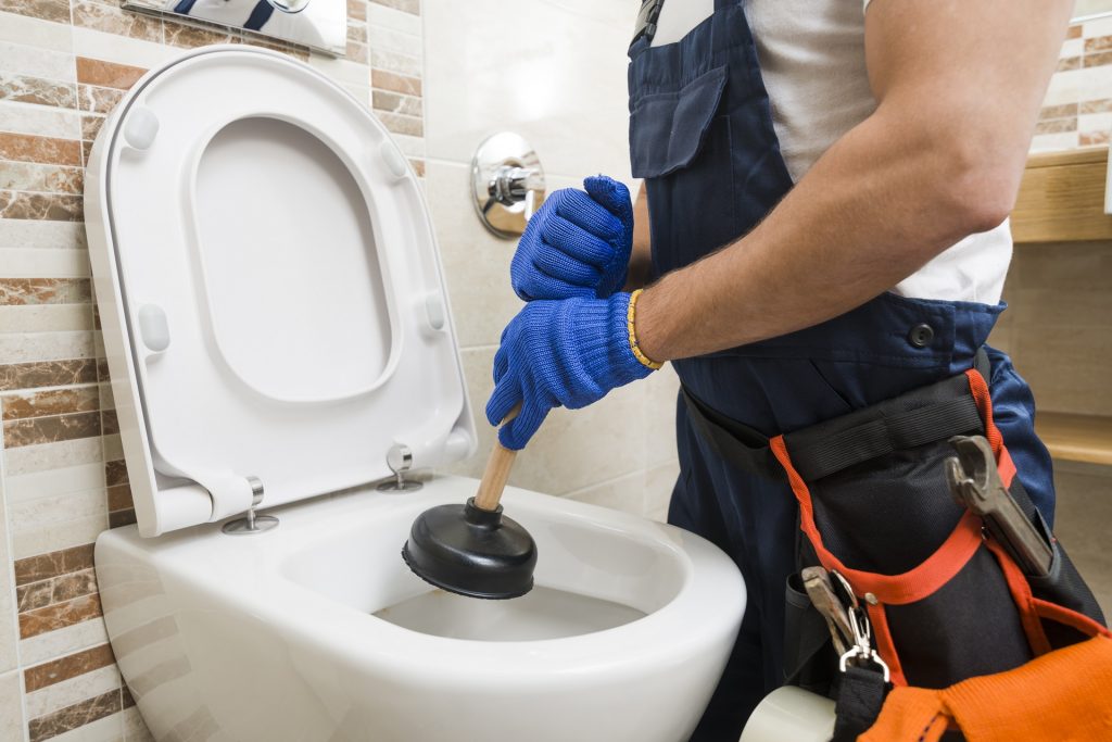 Plumber unclogging a commercial bathroom toilet